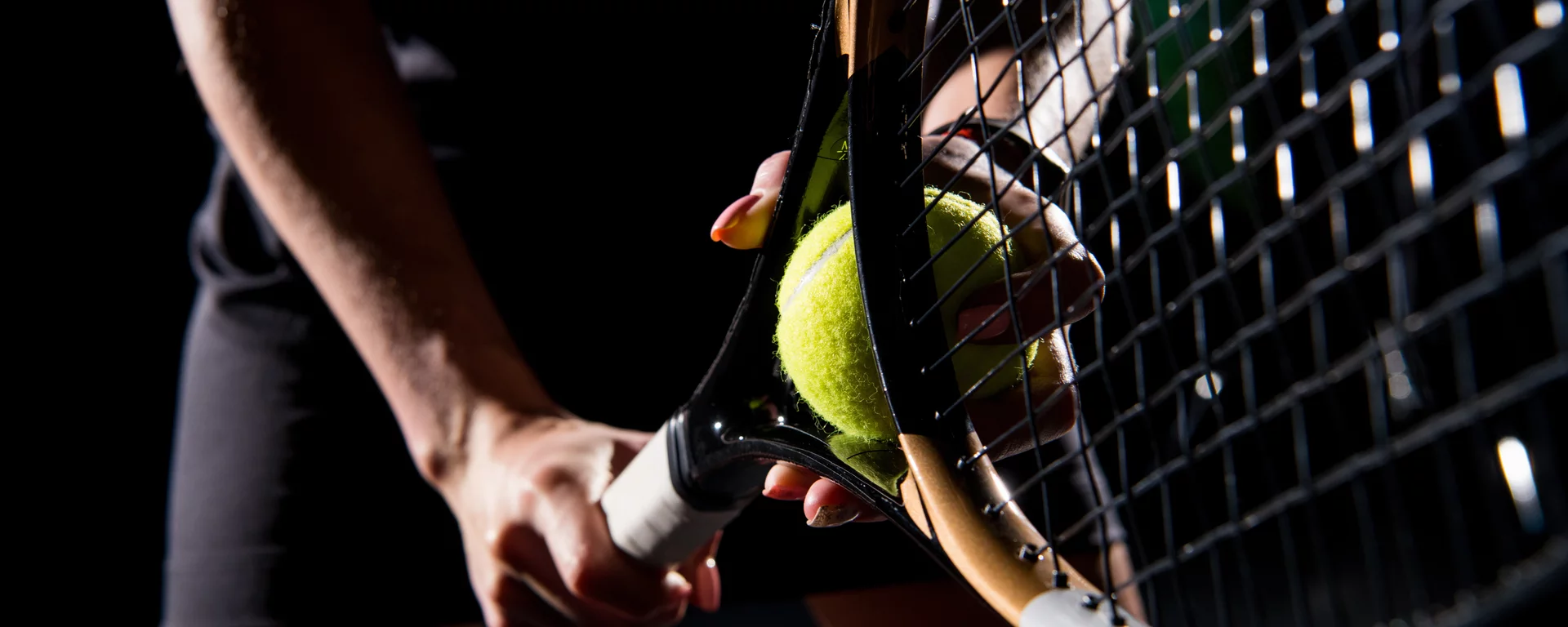 Dramatic close-up shot of tennis racket in a player's hands